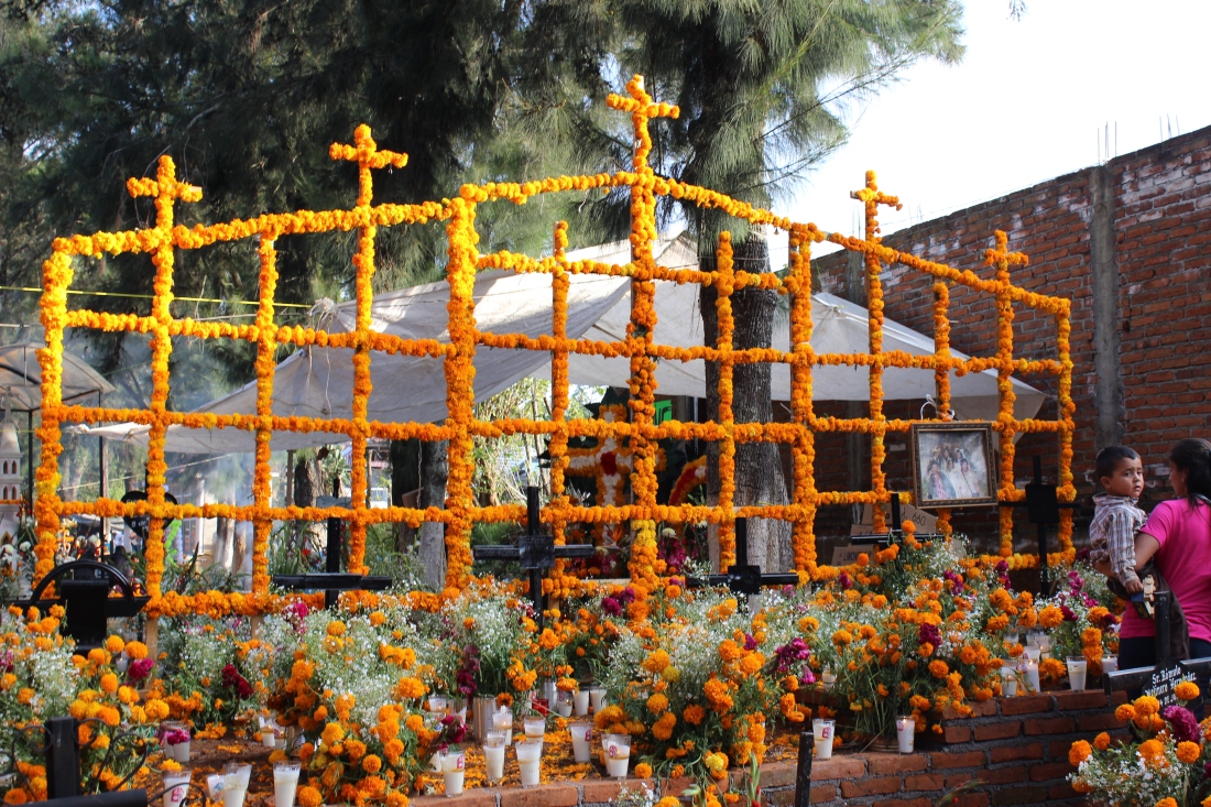 A huge grid-shaped ofrenda in a graveyard in Tzintzuntzan, Michoacán, covered with orange cempasúchil flowers and topped with crosses